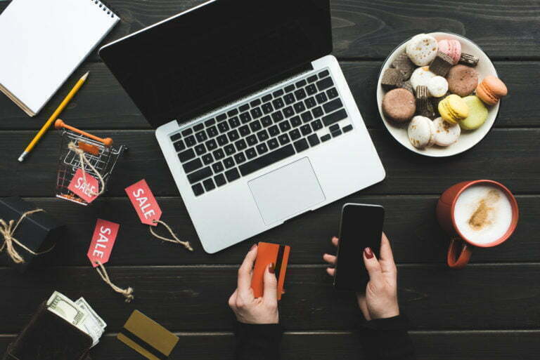 a person holding a cell phone and a laptop