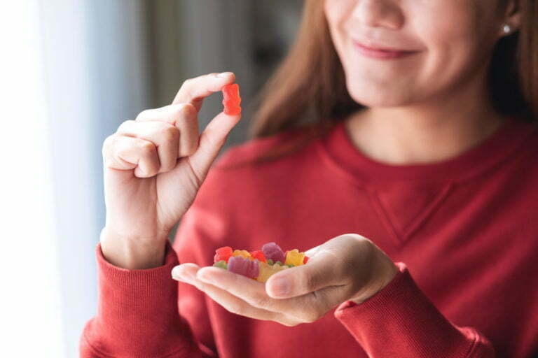 young woman holding and looking at a red jelly gummy bear