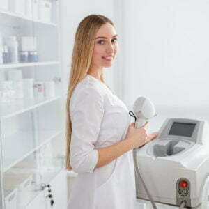 Young woman using laser epilation machine in beauty salon