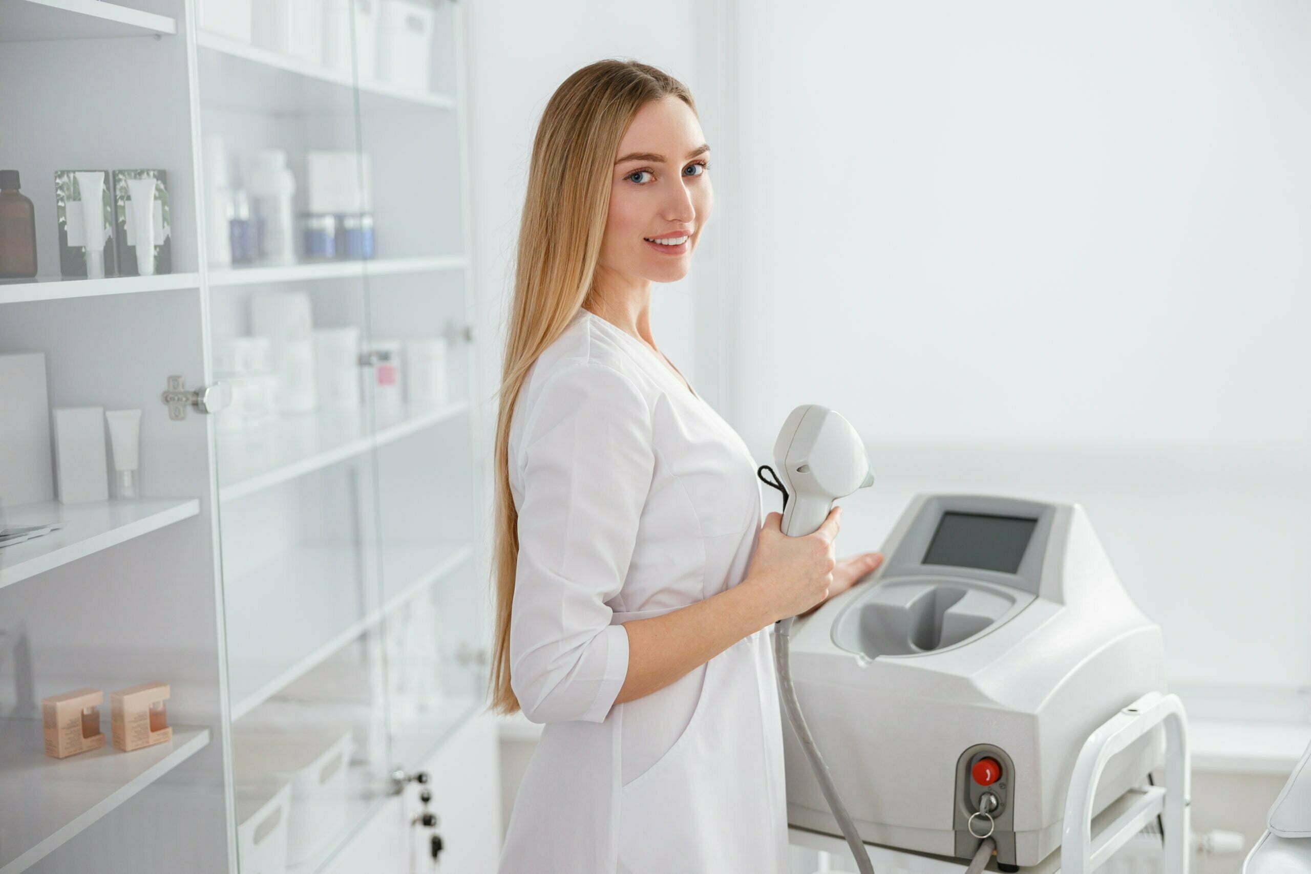 Young woman using laser epilation machine in beauty salon